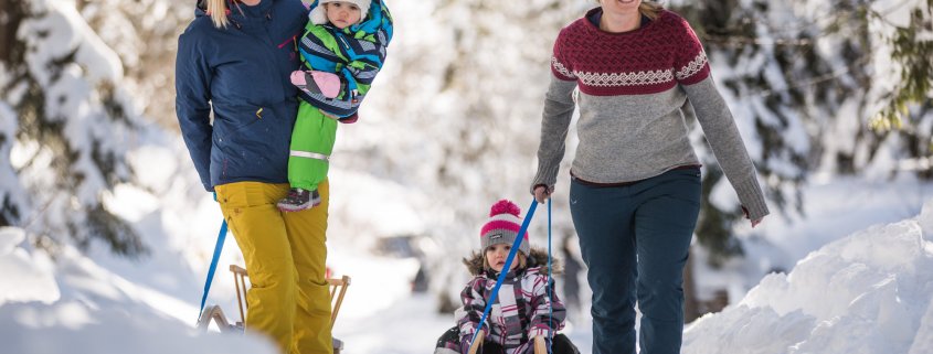 Mamis stapfen mit Kindern und Schlitten durch den Schnee